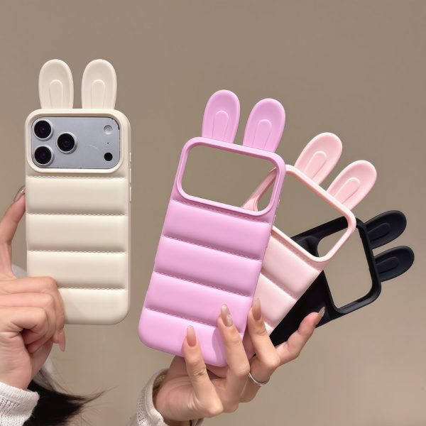 Four Bunny Ear Puffer Phone Cases held by a person, showcasing in various colors such as pink, purple, black, white & cream (Alabaster)