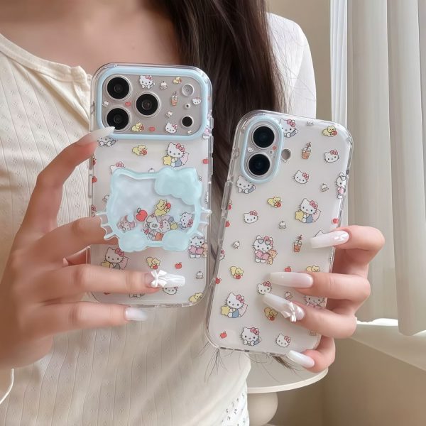 Two clear Hello Kitty phone cases with light blue accents held by a person with long white manicured nails, showcasing cute Sanrio character designs and a matching pop socket.