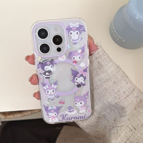 A close-up, top-down photograph of a hand holding a clear iPhone 13 Pro Max with a purple Kuromi MagSafe case. The case features various illustrations of Kuromi characters, a MagSafe ring with clear space inside, and 'Kuromi' text at the bottom. A blue vase is partially visible in the background.